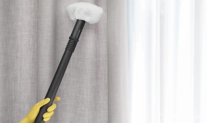Fabric steamer cleaning curtains while hanging