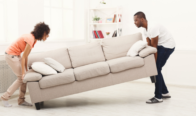 Couple moving heavy furniture - cream sofa
