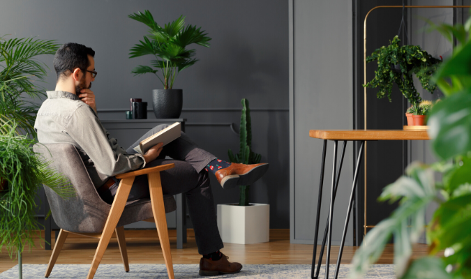 Man Reading In Room With Plants