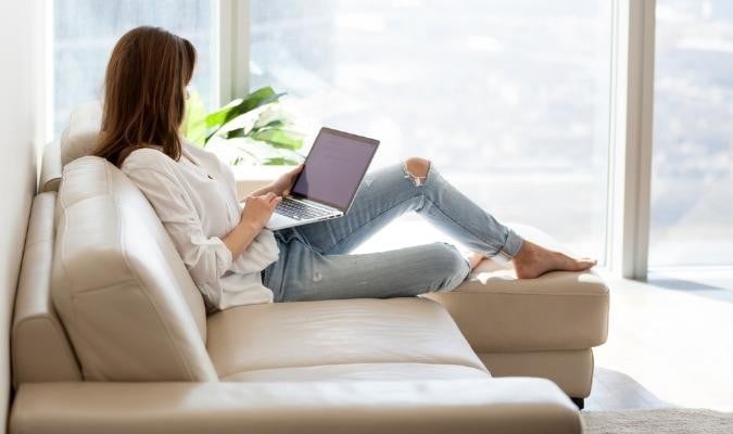 Relaxed -woman -using -laptop -sitting -on -sofa -at -luxury -home -picture -id 994243558