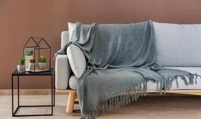 Grey sofa with a blanket in a brown modern living room